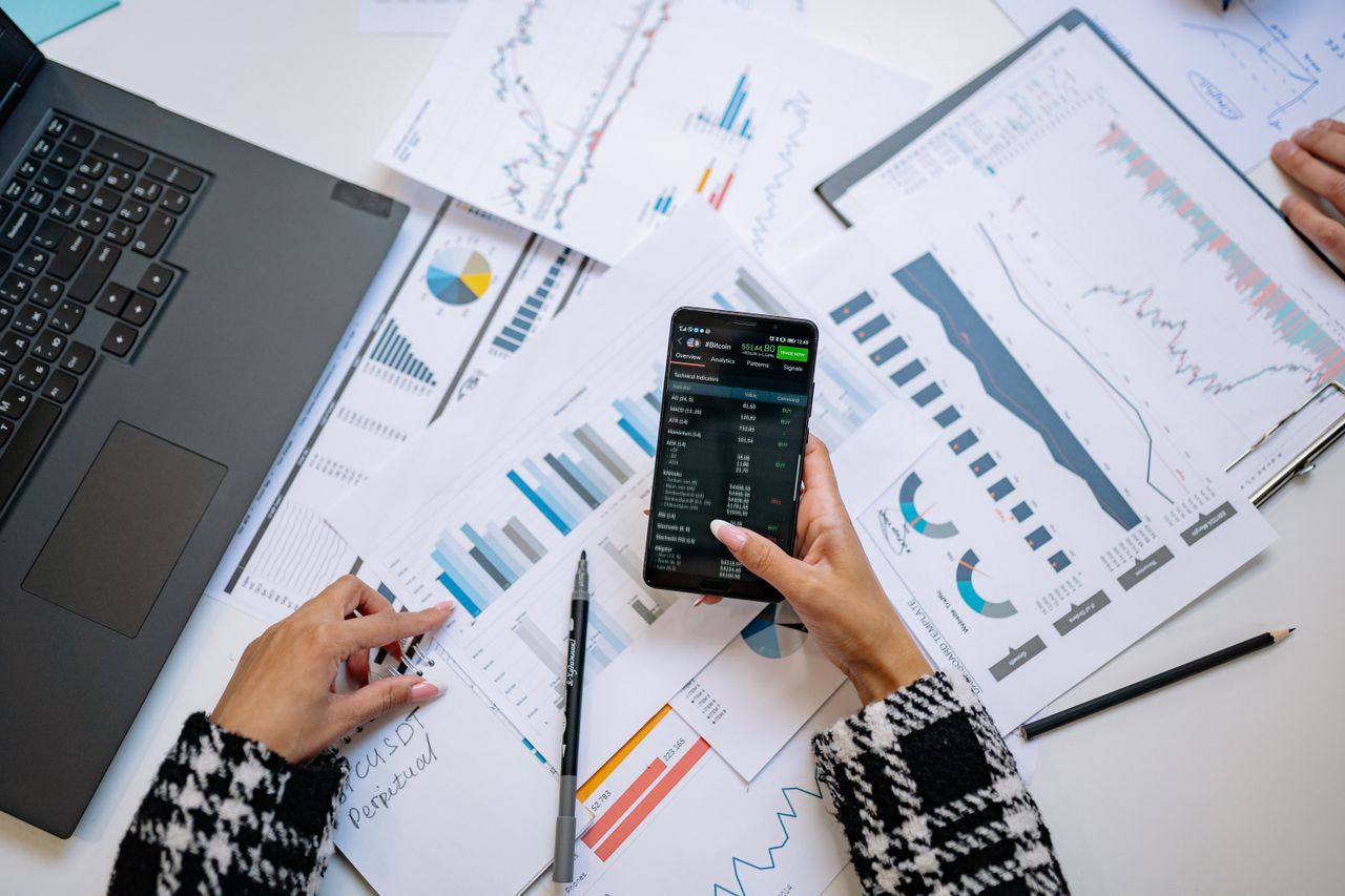 Vue plongeante sur des graphiques et un smartphone dans un bureau, illustrant l’analyse de données.
